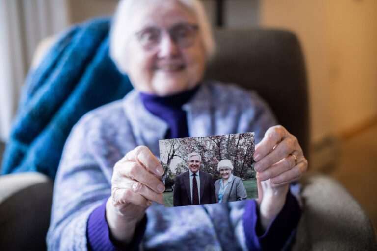elderly woman holding up photograph